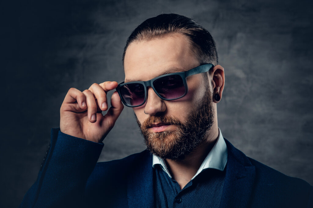 stylish bearded male dressed suit sunglasses dark grey background